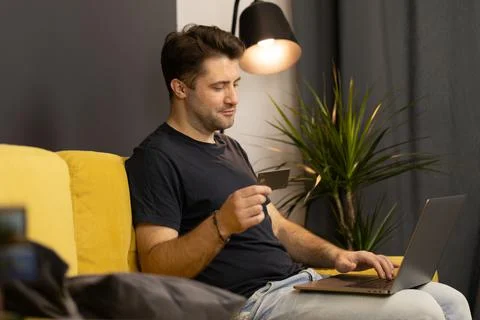 Guy makes purchases or payments online, looks at credit card cvv security code Stock Photos