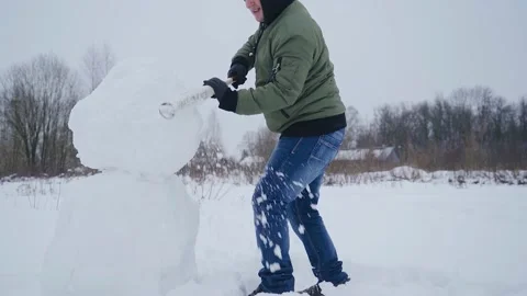 The guy makes a snowman with a baseball bat. Dynamic frames Stock Footage 148028349