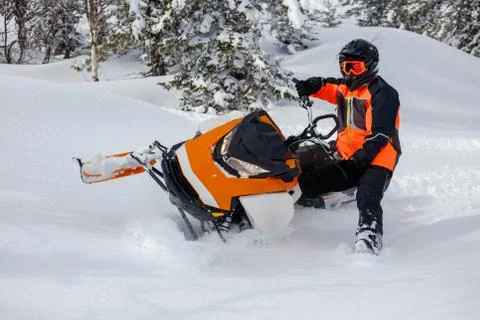 The guy makes a turn on a snowmobile, leaning on his left leg Stock Photos