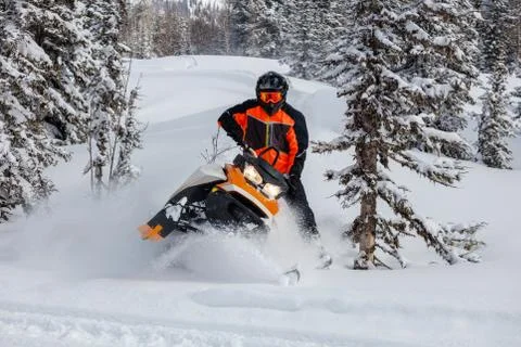 The guy makes a turn on a snowmobile, leaning on his left leg Stock Photos