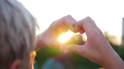 The guy making heart with hands in the sun. Silhouette hand in heart shape with Vidéo 78371100