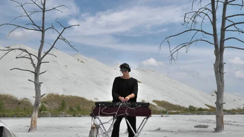 A guy making music at a DJ console in the middle of mountains of chemical waste Stock Footage 172348105
