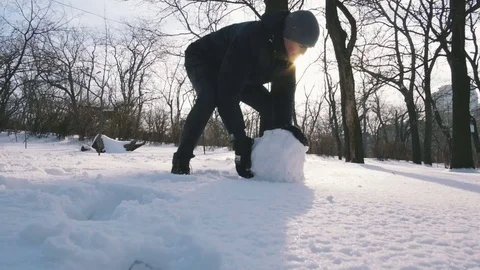 Guy making snowman rolling a huge snowball, slow motion Stock Footage 71554693