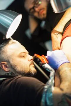 Guy is making tattoo, in a studio. Stock Photos