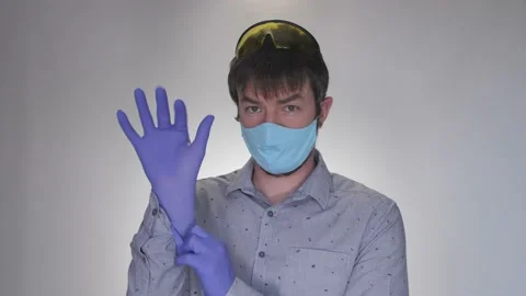 The guy in the mask puts on rubber gloves, yellow glasses and shows that this is Stock-Footage 132024511