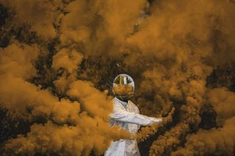 Guy in mask standing in between orange brown smoke bombs Stock Photos