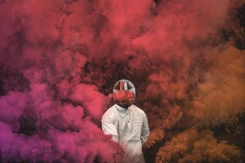 Guy in mask standing in between pink, purple and orange smoke bombs Stock Photos
