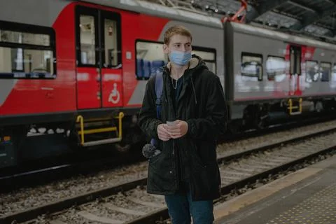 A guy in a mask stands on the platform by the train Stock Photos