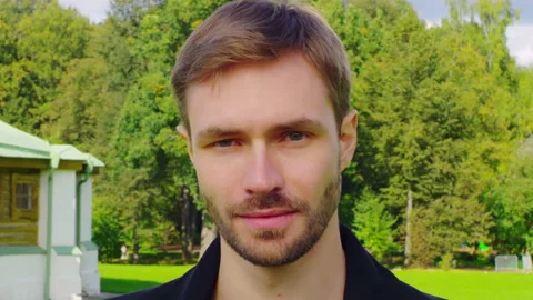 Guy model portrait looks at the camera A beautiful boy in the summer in the park Stock Footage 160334669