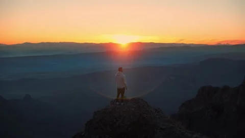 The guy on a morning run standing at the top of mountains . Aerial shot. Stock Footage 239556038