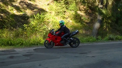 A guy on a motorcycle. Young handsome guy rides a motorcycle on a mountain road. Stock Footage 95907710