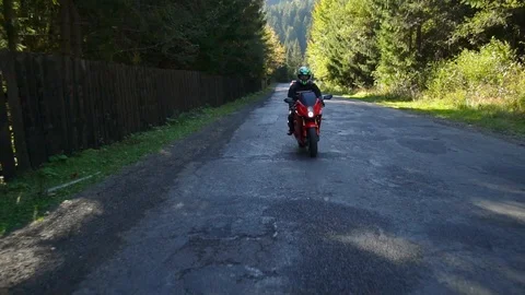 A guy on a motorcycle. Young handsome guy rides a motorcycle on a mountain road. Stock Footage 95908200