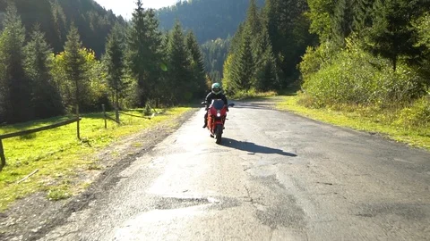 A guy on a motorcycle. Young handsome guy rides a motorcycle on a mountain road. Stock Footage 95908504