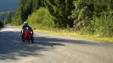 A guy on a motorcycle. Young handsome guy rides a motorcycle on a mountain road. Stock Footage 95909157
