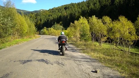 A guy on a motorcycle. Young handsome guy rides a motorcycle on a mountain road. Stock Footage 95910493