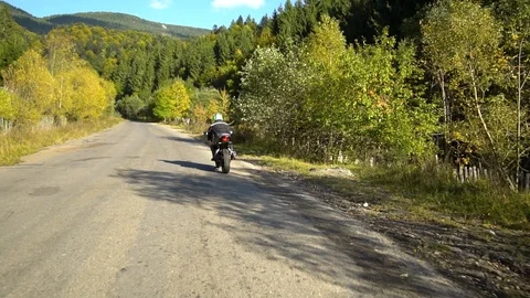 A guy on a motorcycle. Young handsome guy rides a motorcycle on a mountain road. Stock Footage 95910662