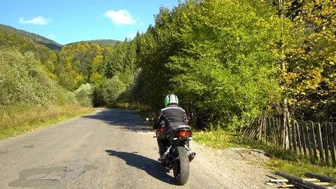 A guy on a motorcycle. Young handsome guy rides a motorcycle on a mountain road. Stock Footage 95910872