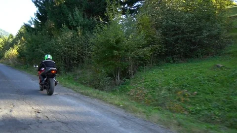 A guy on a motorcycle. Young handsome guy rides a motorcycle on a mountain road. Stock Footage 95911318