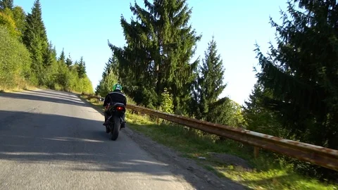 A guy on a motorcycle. Young handsome guy rides a motorcycle on a mountain road. Stock Footage 95970587