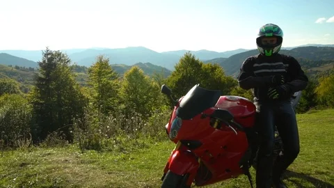 A guy on a motorcycle. Young handsome guy with his motorcycle in the mountains Stock Footage 95970637
