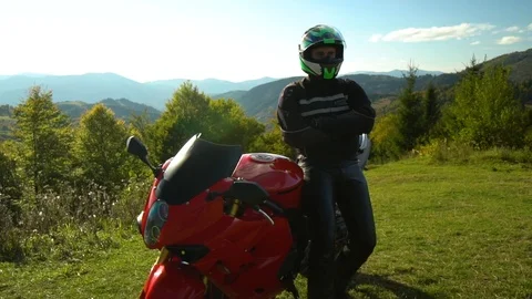 A guy on a motorcycle. Young handsome guy with his motorcycle in the mountains Stock Footage 95970802