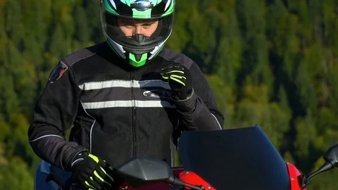 A guy on a motorcycle. Young handsome guy with his motorcycle in the mountains Stock Footage 95980042