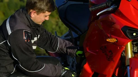 A guy on a motorcycle. Young handsome guy with his motorcycle in the mountains Stock Footage 96044017