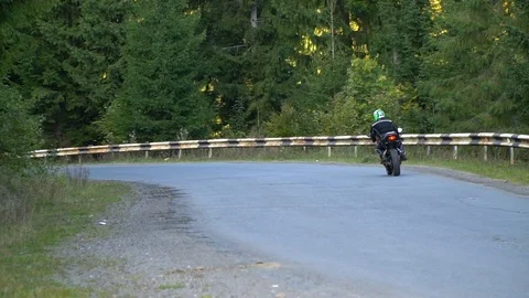A guy on a motorcycle. Young handsome guy rides a motorcycle on a mountain road. Stock Footage 96044849