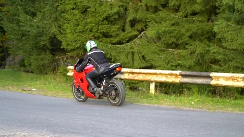 A guy on a motorcycle. Young handsome guy rides a motorcycle on a mountain road. Stock Footage 96152944