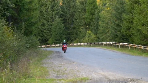A guy on a motorcycle. Young handsome guy rides a motorcycle on a mountain road. Stock Footage 96153064