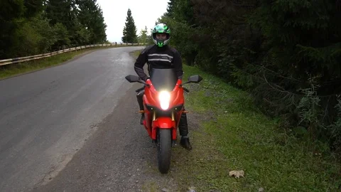 A guy on a motorcycle. Young handsome guy rides a motorcycle on a mountain road Stock Footage 96154406