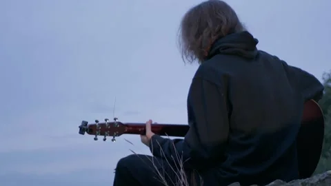A guy in the mountains is hiking and playing the guitar Stock Footage 254933212