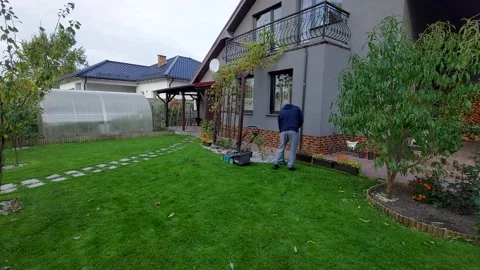 The guy mows the grass in the yard with a trimmer Video stock 162677128
