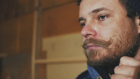 A guy with a mustache and beard with beautiful blue eyes combing his beard Stock Footage 103300144
