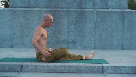 Guy with Naked Torso Does Yoga Exercises Early In the Morning in City Park Stock Footage 85329315