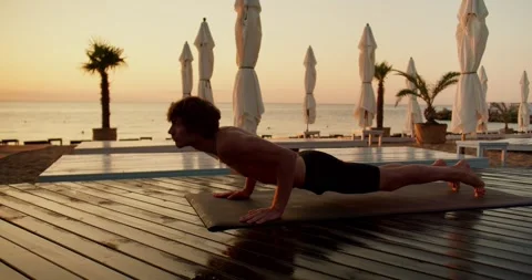 A guy with a naked torso does yoga in the morning. Exercises the cat on a Video stock 249843735