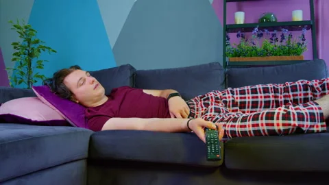 Guy naps on sofa with remote control, shudders 스톡 동영상 161018492