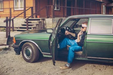 Guy in the nineties sits behind the wheel of a car Smoking a cigarette Stock Photos