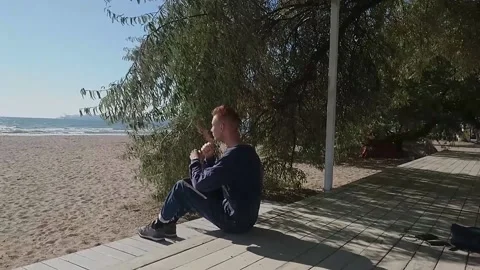 Guy with an old laptop by the sea Stock Footage 167412467