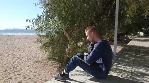 Guy with an old laptop by the sea Stock Footage 167412483