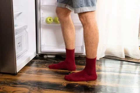 The guy opened an empty refrigerator, his legs close up. Photos