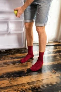 The guy opened an empty refrigerator, his legs close up. 库存照片