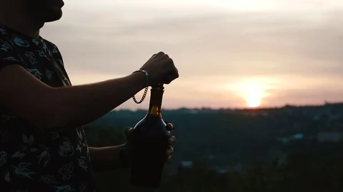 A guy opens a bottle of champagne at sunset Stock Footage 80481071