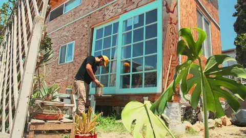 A Guy Outside His Tiny House of Wood in The Morning Doing Gardening Alone Stock Footage 197347622