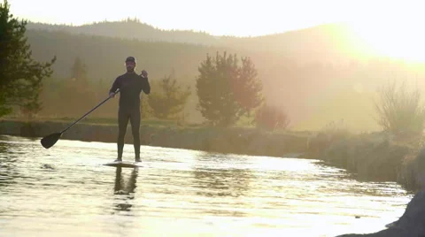 Guy paddle surfs on river Stock Footage 64363222