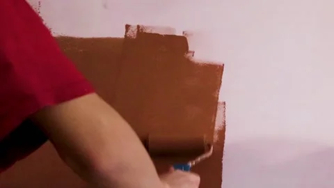 The Guy Paints the Wall With Brown Paint Using a Roller. Builder, Tool. Stock Footage 234334198