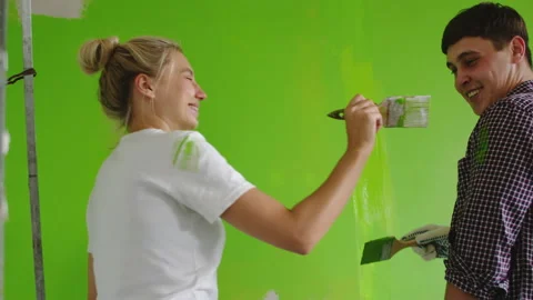 The guy paints the wall with green paint, and the girl smears it with a brush Stock Footage 138642688