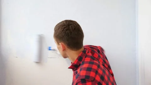 Guy paints wall in grey making repair on spacious terrace Stock-Footage 136095717