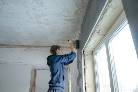 Guy paints the wall with a roller Stock Photos