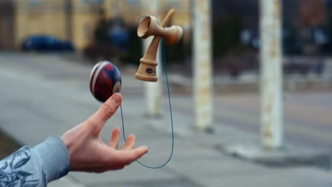 Guy in the park plays Japanese game Magic yoyo Kendama Stock Footage
